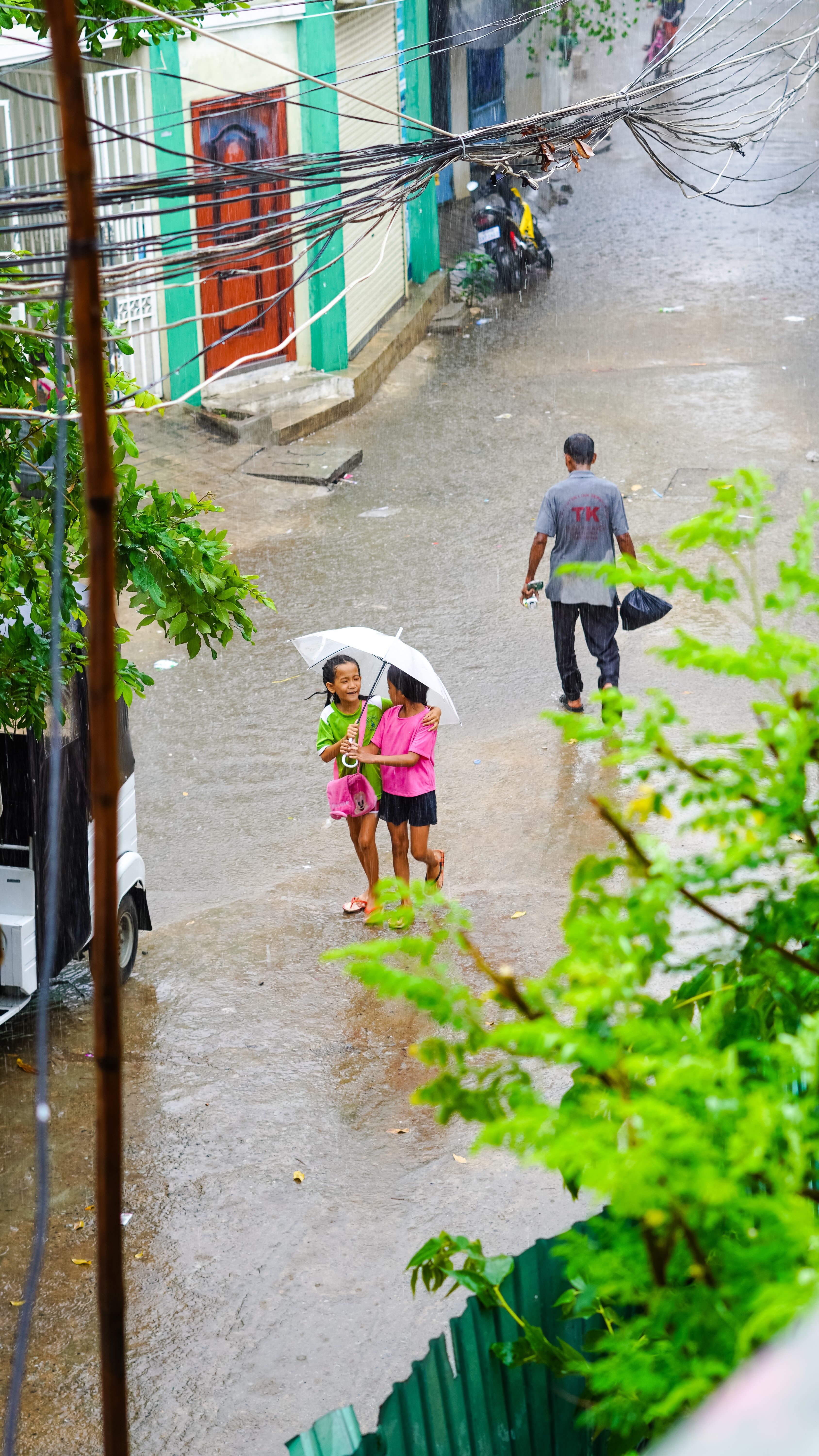2 boys walking on sidewalk holding umbrella during daytime