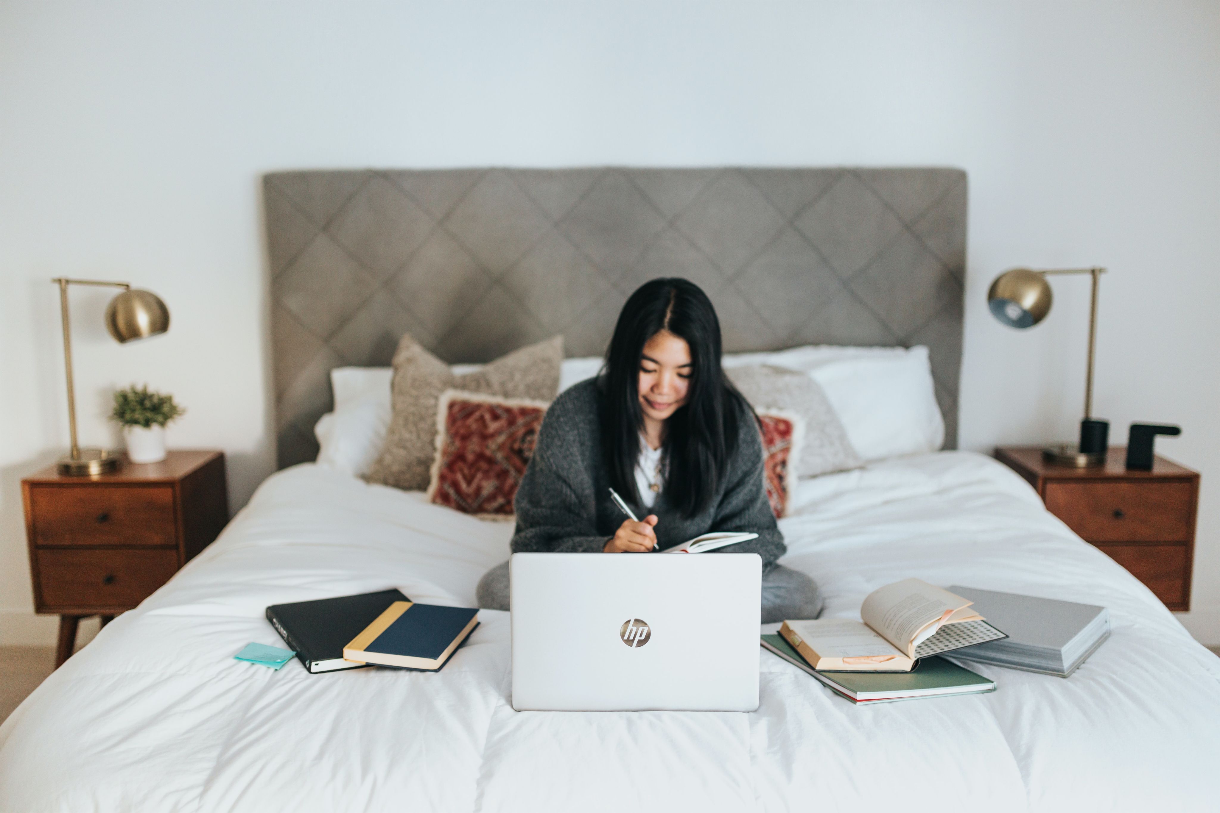 woman in black hijab sitting on bed using laptop