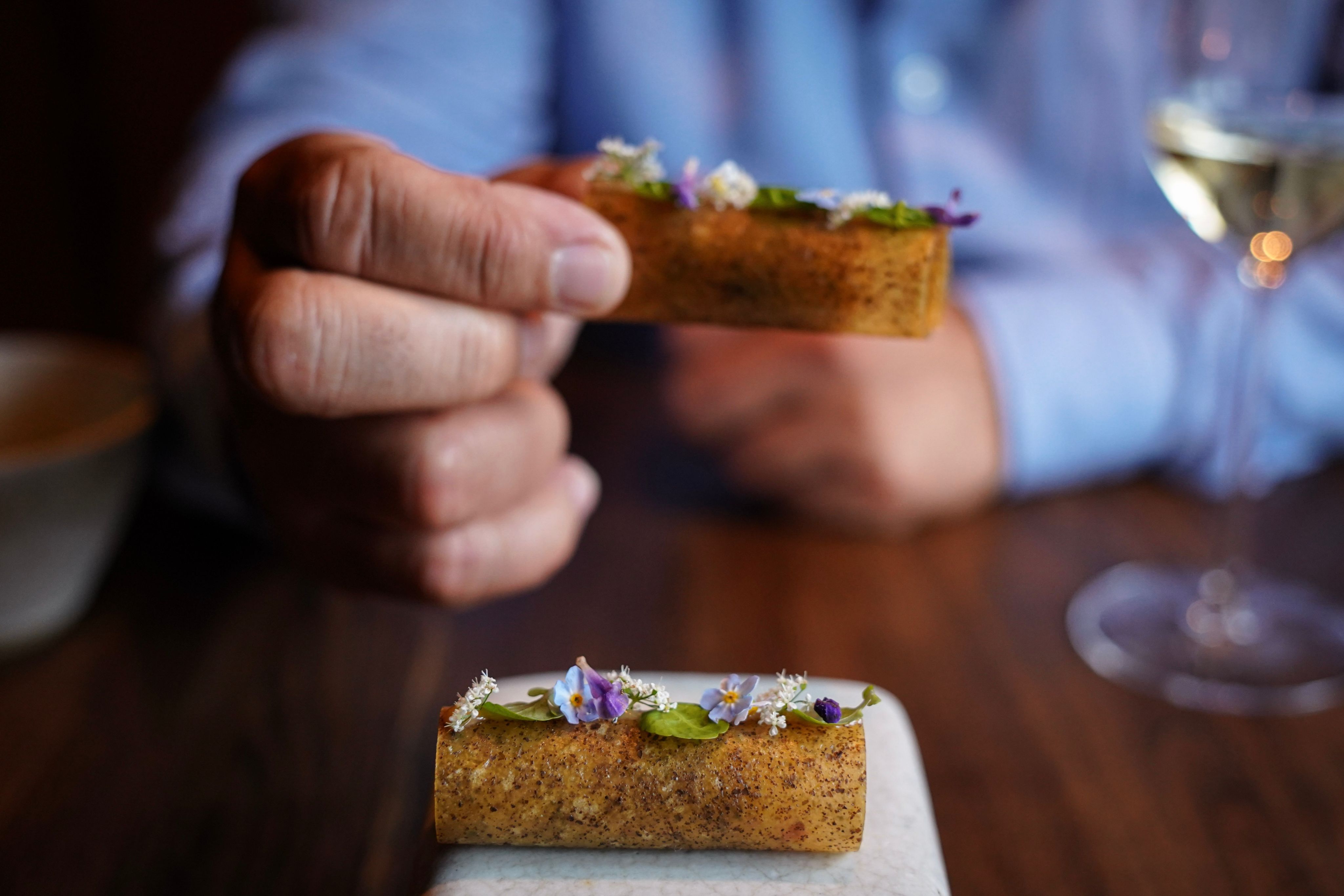 person holding brown bread with green vegetable